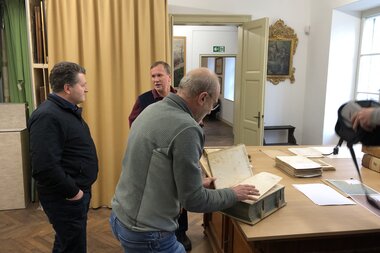 Bad Ischl Raum mit Personen und Buch | © Salzwelten - Pernkopf Altaussee Buch historisch Salinenarchiv | © Salzwelten - Pernkopf