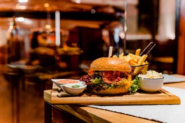 Brästübl Kaltenhausen Package mit Salzwelten Salzburg Burger mit Pommes Rot/Oranger Hintergrund  | © Brau Union AG